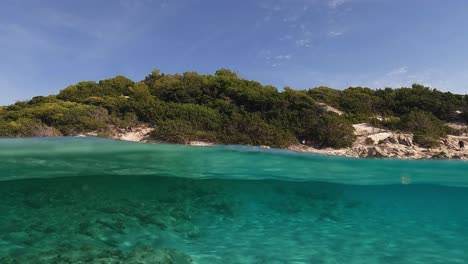 Half-underwater-point-of-view-of-amazing-beauty-of-Saleccia-beach-nature-in-Corsica-island,-France