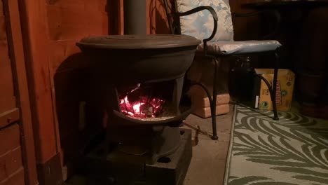 Estufa-De-Leña-De-Hierro-Fundido-Ardiendo-En-La-Acogedora-Cocina-De-Cabaña-De-Madera-Al-Aire-Libre