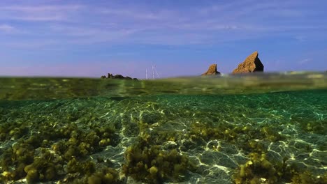Meerwasser-Oberflächenperspektive-Des-Segelschiffs-Am-Horizont-Mit-Segeln,-Die-Zwischen-Felsen-Gesenkt-Werden