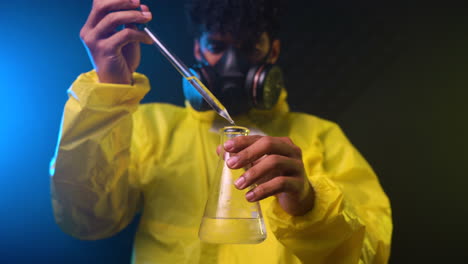 Chemist-with-the-gas-mask-and-the-protective-suit-in-Hazmat-Suit-Handling-Hazardous-Chemicals-in-a-sterilised-container