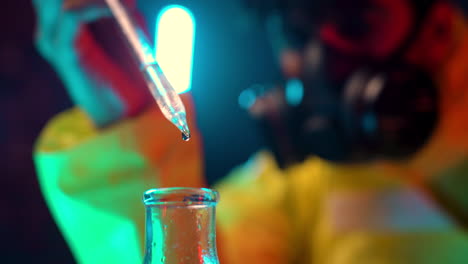 close-up-of-chemical-pipette-dropping-transparent-liquid-in-to-lab-tubes-with-blurred-scientist-chemist-wearing-respiratory-mask-in-background