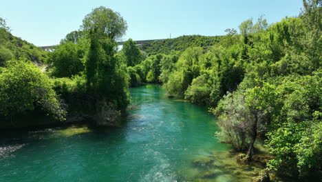 Fast-flowing-river-in-Bosnia-surrounded-by-lush-green-landscapes