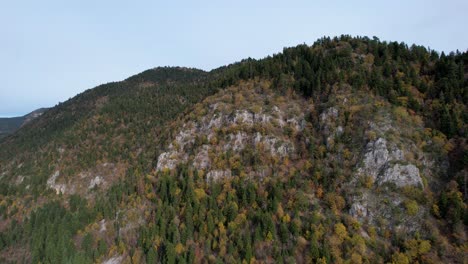 Colorful-foliage-of-mountain-range-covered-by-forests-with-pines-and-bushes-in-Autumn