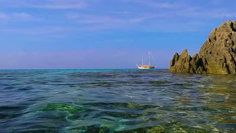 Sea-water-surface-perspective-of-sailing-ship-on-the-horizon-between-rocks