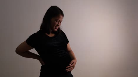 Mujer-Embarazada-Asiática-Que-Sufre-De-Dolor-De-Espalda-En-La-Habitación-Oscura-En-Casa