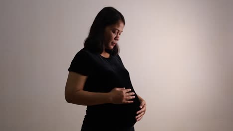 Asiatische-Schwangere-Frau,-Die-Unter-Rückenschmerzen-Leidet,-Während-Sie-Ihren-Bauch-Streichelt