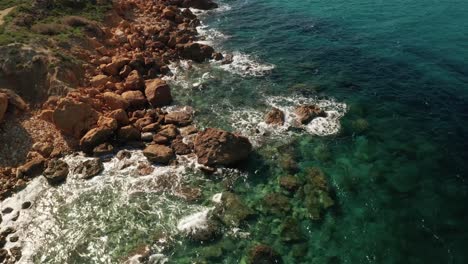 Aerial-high-angle-tilt-down-drone-shot-of-beautiful-turquoise-water-near-Rampla-Beach-on-the-Island-Gozo,-Malta