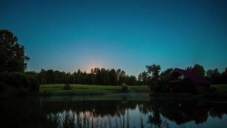 Zeitrafferaufnahme-Des-Sonnenuntergangs-Im-Hintergrund-Mit-Blick-Auf-Einen-See-Vor-Einem-Holzhaus-An-Einem-Nebligen-Abend