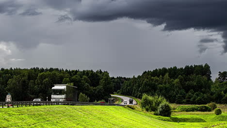Timelapse-shot-of-dark-cloud-movement-over-traffic-movement-over-highway-surrounded-by-green-grasslands-and-trees-on-a-cloudy-day