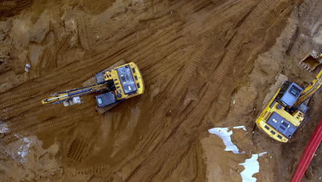 Birdseye-Drone-Aerial-ascend-worksite-multiple-yellow-excavators-digging-dirt-mud