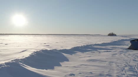 2-Women-looking-out-across-frozen-lake,-drone,-tundra