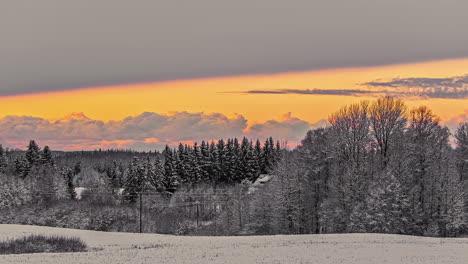 Timelapse-shot-over-cold-winter-rural-snow-covered-landscape-beside-a-cottage-on-a-cloudy-evening