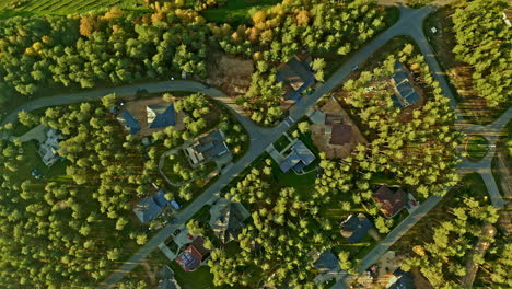 Aerial-drone-bird's-eye-view-over-beautiful-town-houses-surrounded-by-dense-vegetation-during-evening-time