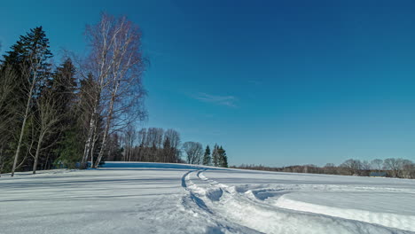 Zeitrafferaufnahme-über-Schneebedecktes-Feld-Den-Ganzen-Tag-über-Mit-Sonnenuntergang-Im-Hintergrund-Hinter-Der-Silhouette-Von-Bäumen