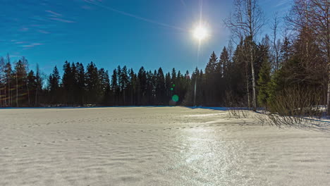All-day-time-lapse-as-the-sun-flares-across-the-sky-over-a-winter-clearing-in-the-forest