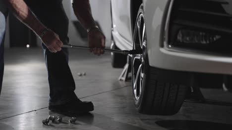 Unrecognizable-mechanic-removing-lug-nuts-from-car-wheel-with-lug-wrench,-slow-motion
