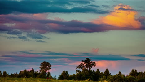 Low-angle-shot-of-heavy-cloud-movement-in-timelapse-above-rural-grasslands-surrounded-by-trees-during-evening-time-after-sunset