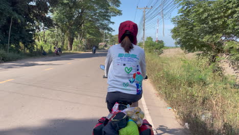 Rückenschuss-Von-Frauen,-Die-Auf-Der-Straße-Von-Laos-Radeln