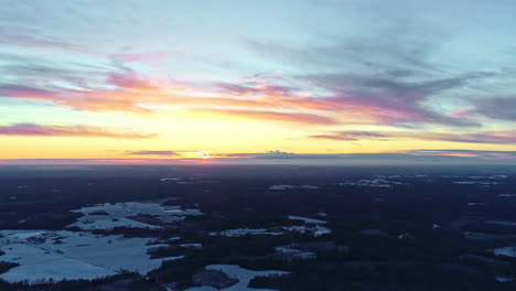 Hochwinkelaufnahme-über-Winterlandschaft-Mit-Schneebedecktem-Wald-Am-Straßenrand-Mit-Leuchtend-Gelbem-Himmel-Bei-Sonnenaufgang-über-Dem-Horizont