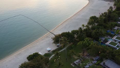 Luftvogelperspektive-überführung-Danna-Beachfront-Resort-Hotel-Schwimmbad,-Fliegen-Am-Pantai-Kok-Strand-Entlang,-Neigung-Nach-Oben-Offenbart-Tropische-Sonnenunterganglandschaft-Mit-Inselsilhouette-Pulau-Burau,-Langkawi,-Malaysia