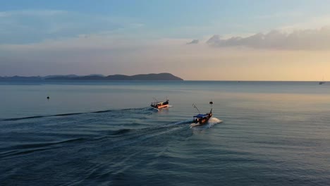 Aerial-drone-fly-around-two-fishing-boats-sailing-into-the-ocean-to-catch-fish-at-sunset-golden-hour,-Langkawi-island,-Kedah,-Malaysia,-Southeast-Asia
