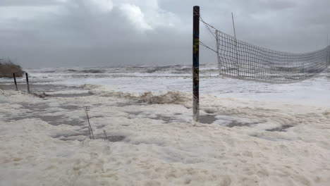 Waves-and-sea-foam-from-Hurricane-Nicole-flood-Florida-beach-volleyball-court