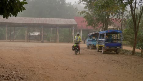Young-Asian-woman-riding-a-bike-in-a-rural-Southeast-Asian-village-in-foggy-conditions
