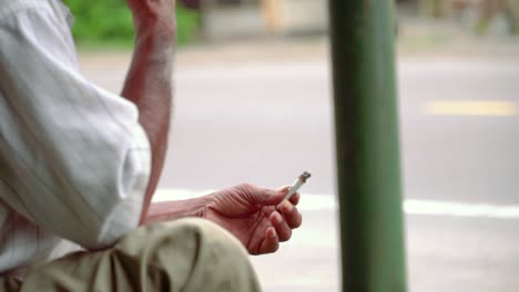 Slow-motion---close-up-shot-of-hand-of-poorman-holding-a-cigarette-on-the-side-of-road