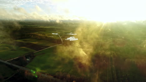 Drohne-Fliegt-Durch-Wolken-Mit-Grüner-Landschaft-Im-Hintergrund