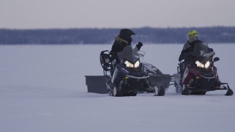 2-Motos-De-Nieve-Conduciendo-Y-Deteniéndose-En-Un-Lago-Congelado