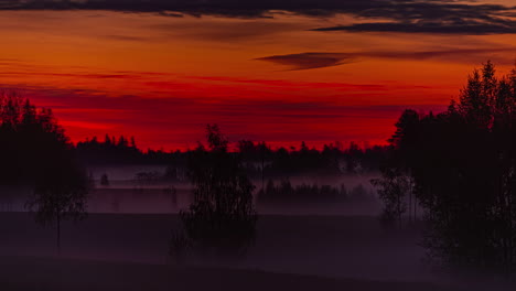 Vibrant-dark-red-color-sky-of-sunrise-and-misty-rural-landscape,-fusion-time-lapse
