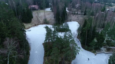 Ice-Skating-on-a-frozen-pond,-river-or-flooded-public-park---aerial-tilt-up-reveal