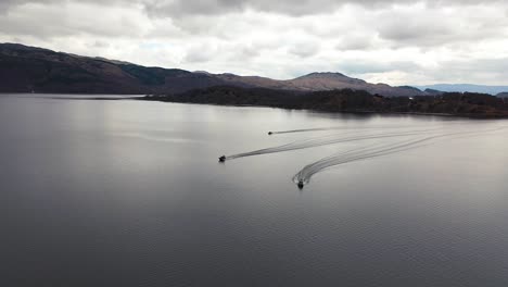 Cinematic-aerial-slow-mo-high-to-low-drone-angle-of-3-boats-cruising-on-Loch-Lomond-in-early-spring