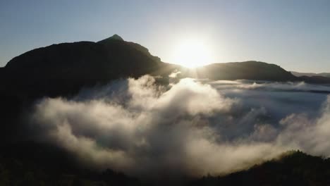 Vista-De-Drones-Sobre-Las-Nubes-Con-Las-Montañas-A-Lo-Lejos-Y-El-Amanecer