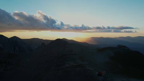 breathtaking-sunset-from-a-drone-shot-going-backwards-on-a-high-altitude-revealing-the-mountain-horizon-and-a-refuge-for-hikers-and-climbers