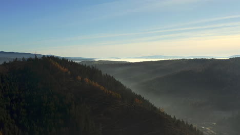 Peaceful-aerial-over-Hasmas-Mountains,-village-of-Balan-in-foggy-valley,-Romania