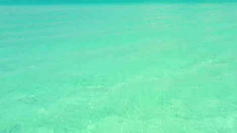 Drone-up-off-of-water-to-reveal-beach-paradise,-Exuma,-Bahamas-4K,-UHD