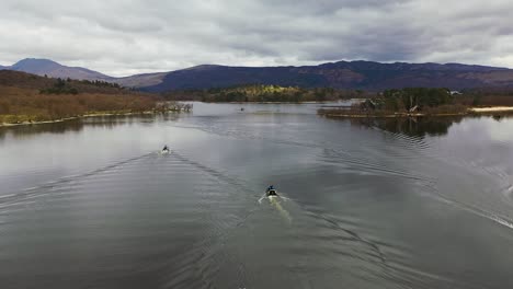 Filmische-Zeitlupenperspektive-Eines-Drohnenvorbeiflugs,-Der-Drei-Booten-Folgt,-Die-Sich-Den-Engstellen-Am-Loch-Lomond-In-Schottland-Nähern