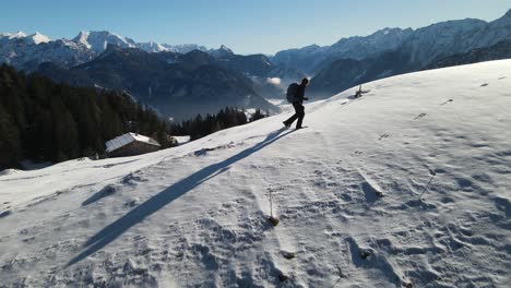 Young-man-hikes-in-the-snow-with-view-over-austrian-mountains-in-snowshoes