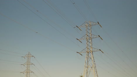 Zwei-Elektrische-Sendemasten,-Die-Tagsüber-Vor-Einem-Blauen,-Klaren-Himmel-Stehen