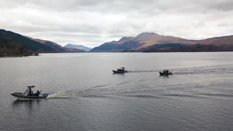 Cinematic-Slow-Mo-Aerial-Shot-Sweeping-Around-Three-Boats-Cruising-On-Loch-Lomond-Scotland-With-Ben-Lomond-In-The-Background-In-Early-Spring