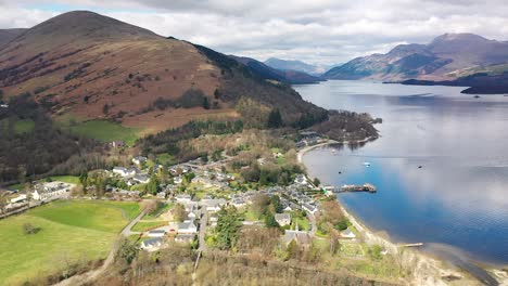 Aerial-Angle-of-Pan-Around-Village-of-Luss-Loch-Lomond-Pan-From-Ben-Lomond-To-Reveal-The-Village-And-Valley-Behind-In-Early-Spring