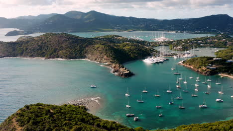 Sunny-aerial-shot-of-English-Harbor-in-Antigua,-Caribbean-with-views-of-yachts,-sailboats,-marina,-bay-and-cliffs