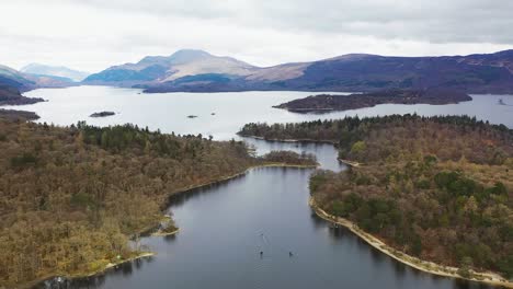 Aerial-slowmo-drone-angle-of-boats-travelling-through-the-narrows-on-Loch-Lomond,-Scotland,-with-Luss-and-Ben-Lomond-in-the-background-in-early-spring