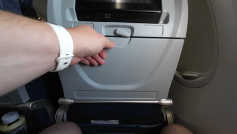 Folding-an-airplane-tray-table-up-and-locking-it-in-the-upright-position