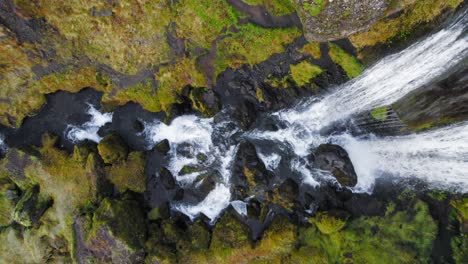 Water-From-Waterfall-Falling-On-Rocks-And-Flowing-Down-River-Stream-With-Mossy-River-Bank