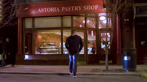 Man-walks-across-road-to-pastry-shop