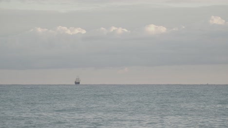 16th-Century-Galleon-Andalucia-replica-ship-sailing-in-the-distance-in-the-calm-Mediterranean-sea-in-a-cloudy-day-at-sunrise