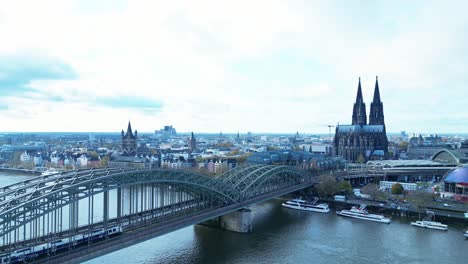 Bridge-over-the-Rhein-river-in-Cologne,-Germany-on-a-cold-Autumn-morning-with-the-Cologne-Cathedral-on-the-background-and-a-train-passing-by