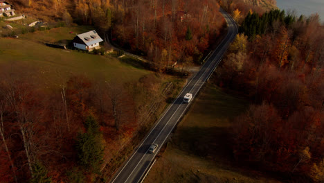 Aerial-shot-of-a-camper-van-driving-on-a-winding-paved-country-road,-traveling